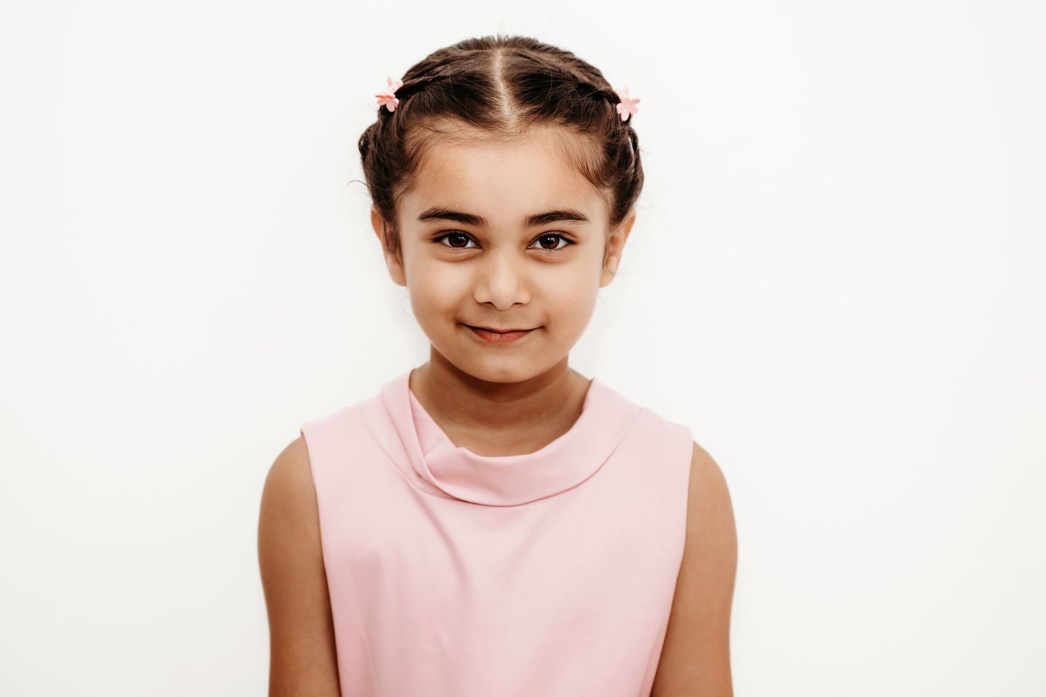 Portrait of child wearing pink sleeveless top against white background.