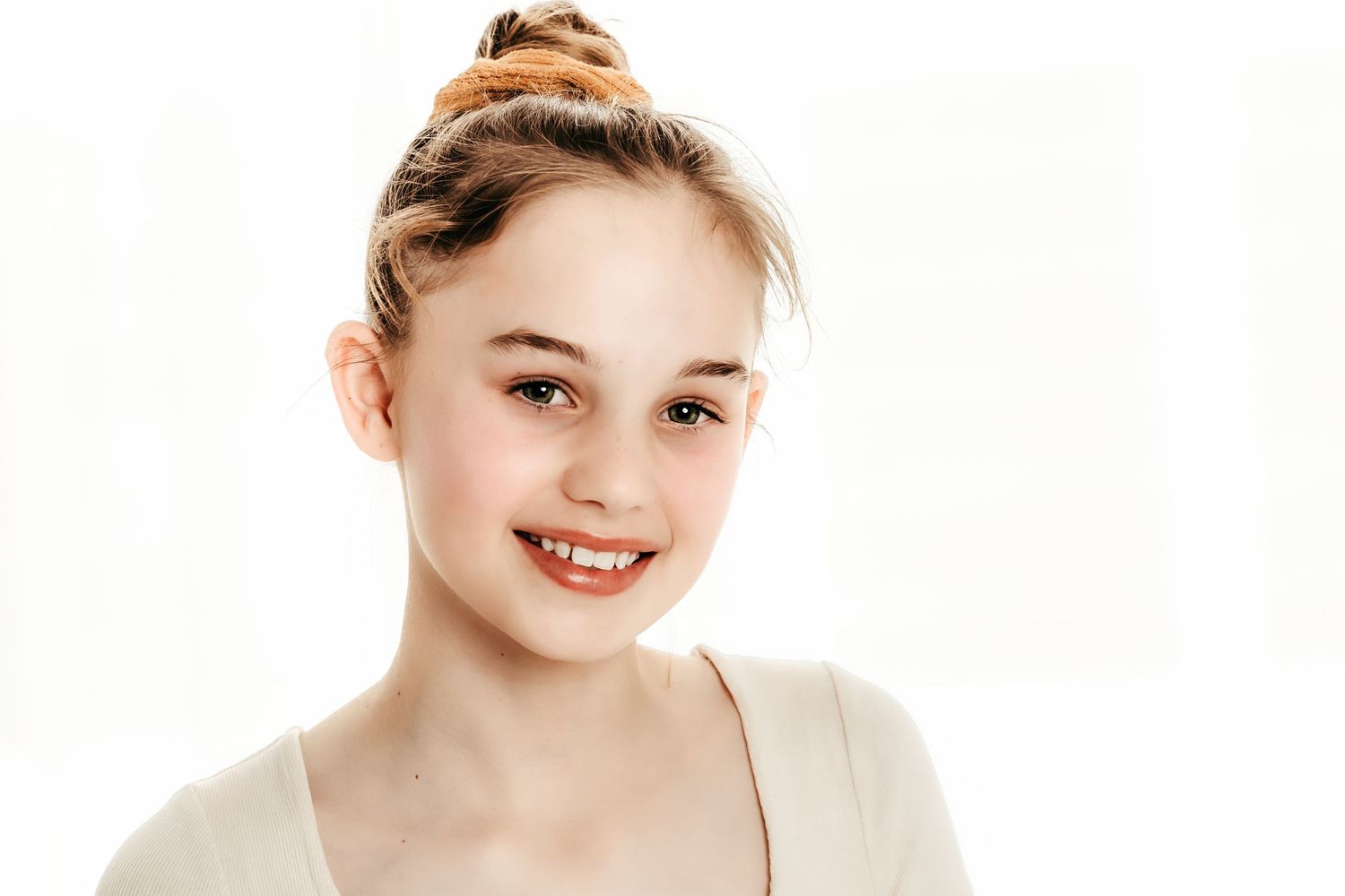 A dancer in white poses against a bright studio background with natural lighting.