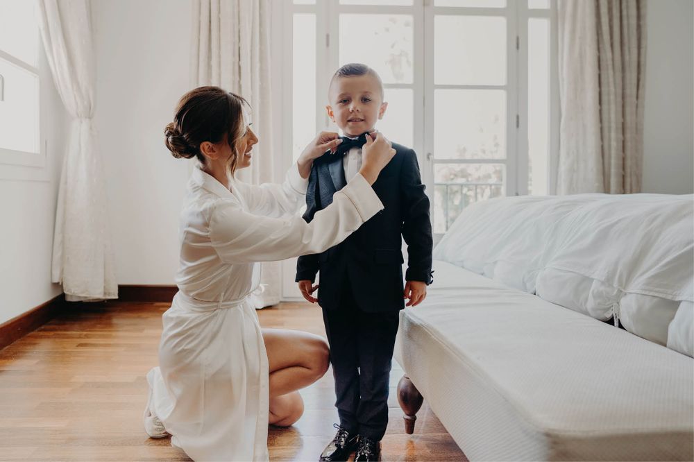 A tender moment during wedding preparations in a bright, sunlit room.