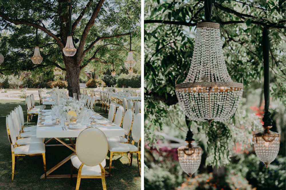 Outdoor wedding reception tables under crystal chandeliers hanging from trees.