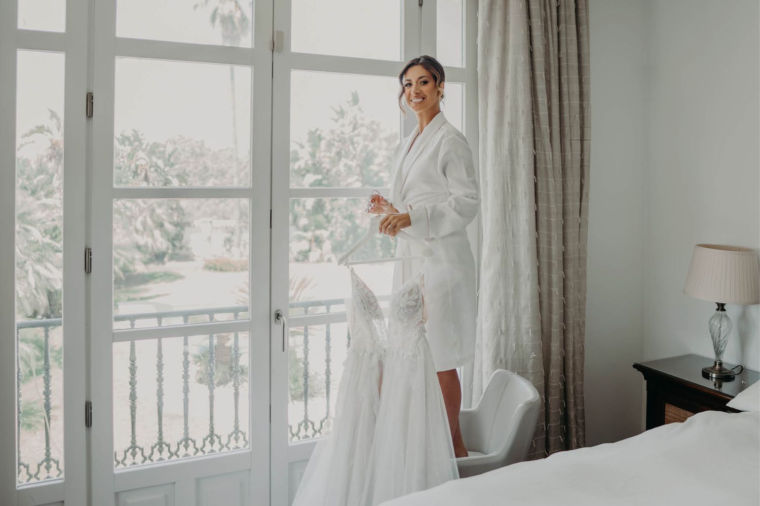 Bridal preparation scene in bright hotel room with French doors.
