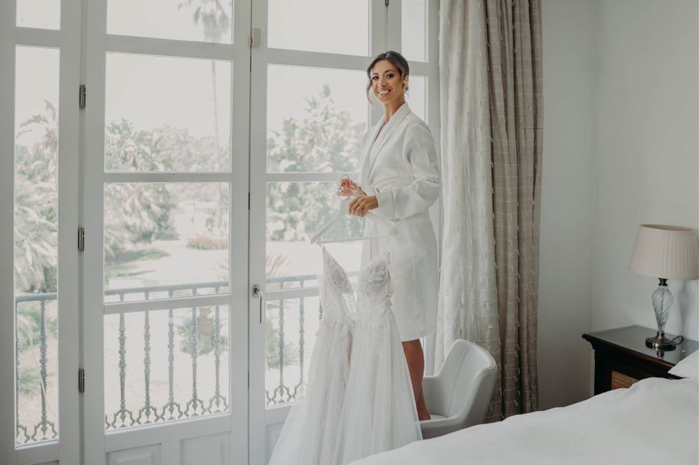 Bridal preparation scene in bright hotel room with French doors.