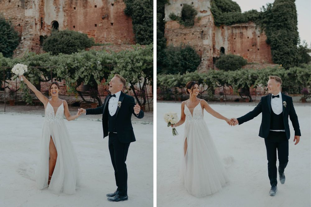 Wedding couple celebrates joyfully against ancient stone walls in romantic outdoor setting.