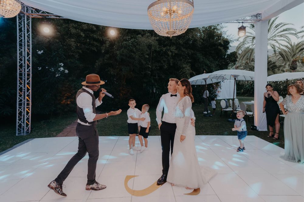 Wedding reception features entertainment on an outdoor dance floor under string lights.