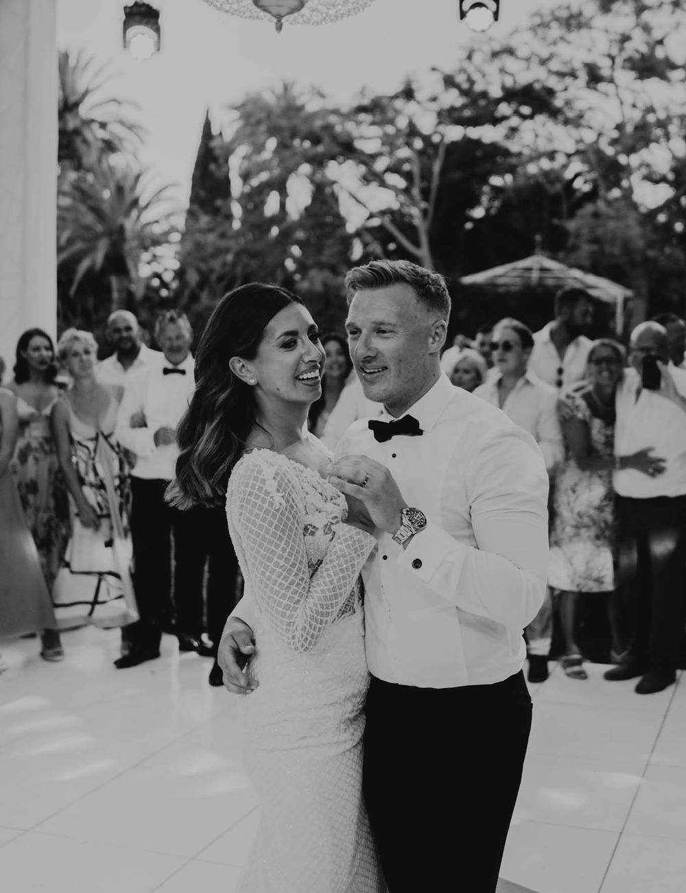 Black and white photo of couple dancing at outdoor wedding reception.