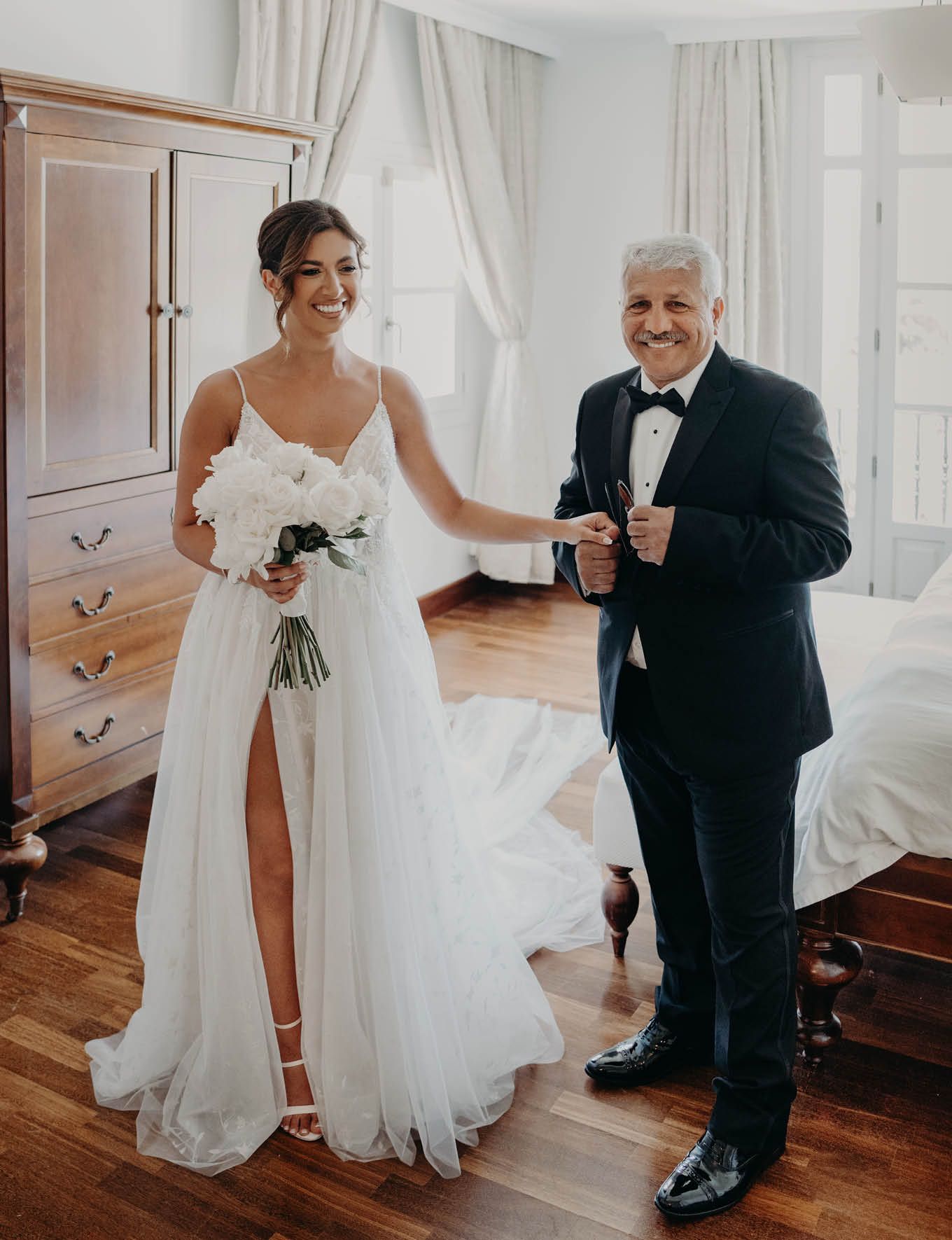 A touching wedding day moment captured in a bright room with hardwood floors.