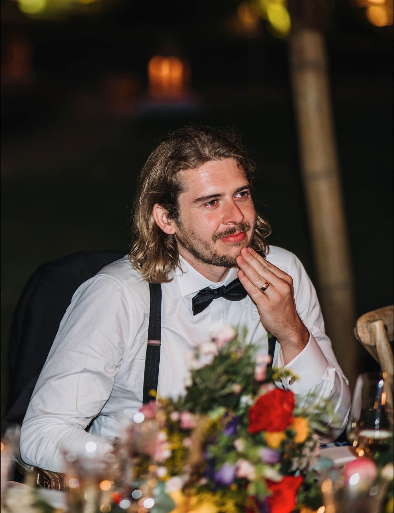 Guest enjoying dinner at an outdoor wedding reception with floral centerpieces.