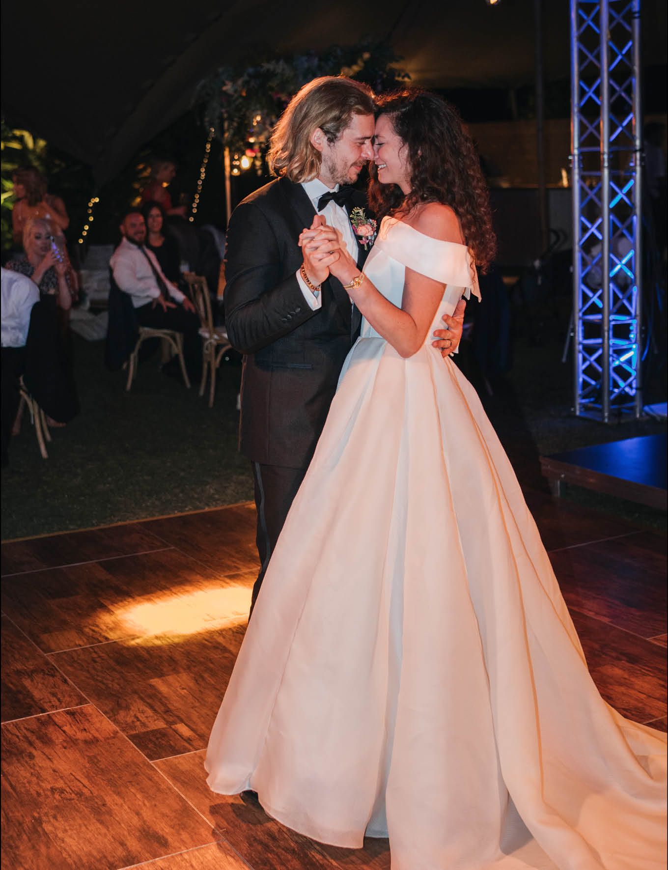 Romantic first dance moment on wooden dance floor at evening reception.
