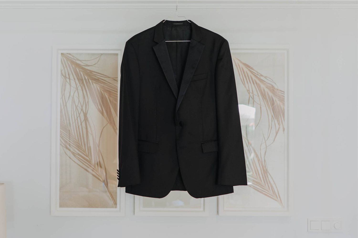 Classic black suit jacket displayed against neutral artwork background.