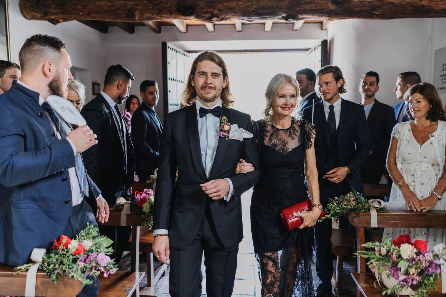 Indoor wedding ceremony with elegant floral arrangements and rustic wooden beams.