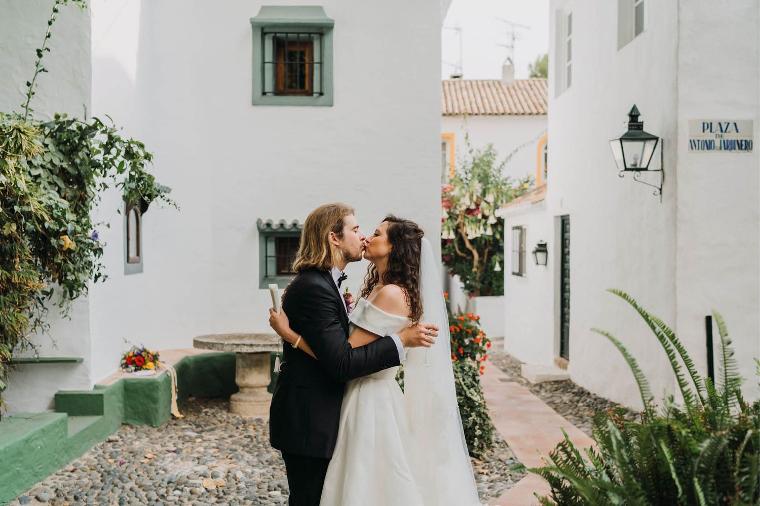 A couple shares an intimate moment in a charming white-walled Mediterranean courtyard.