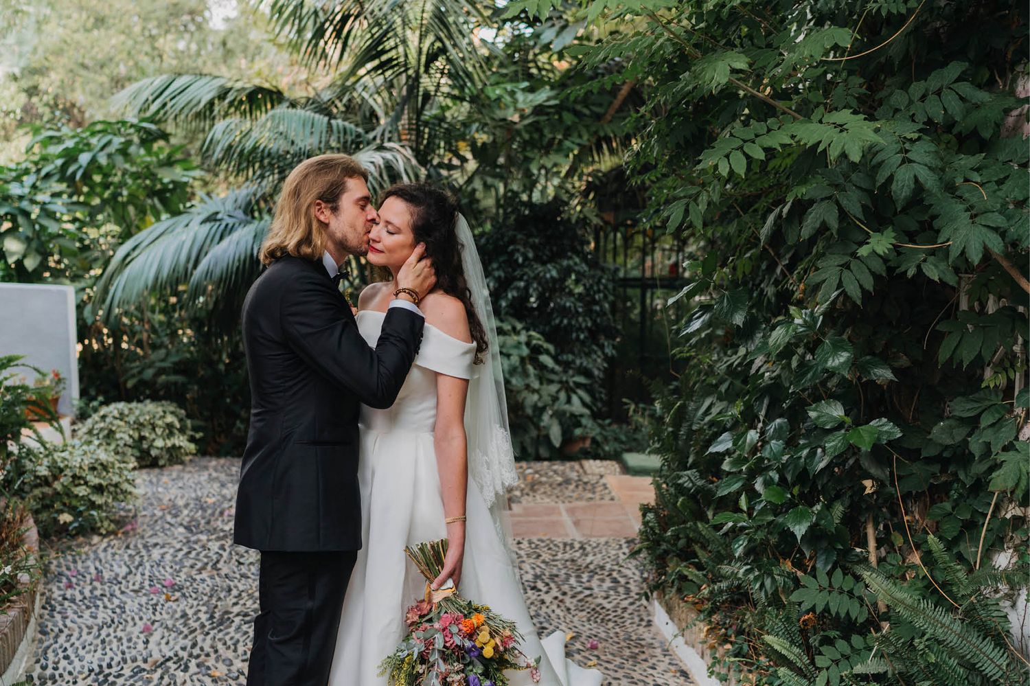 A romantic moment captured in a lush tropical garden setting.