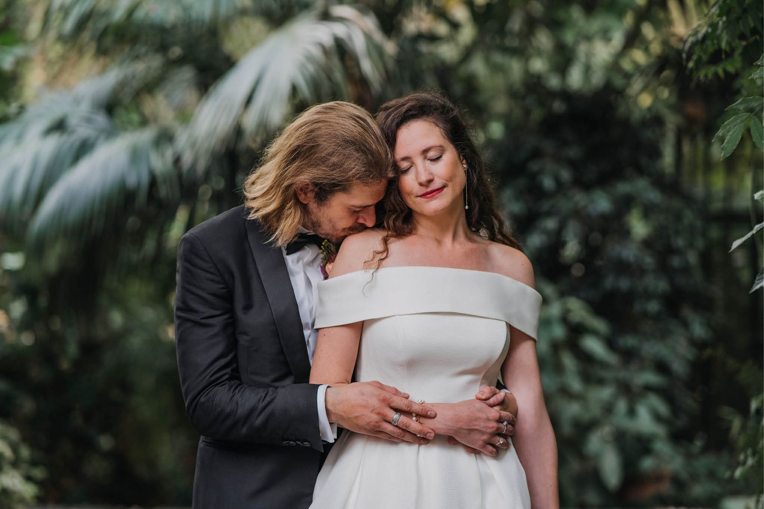 An intimate wedding portrait amidst tropical foliage.