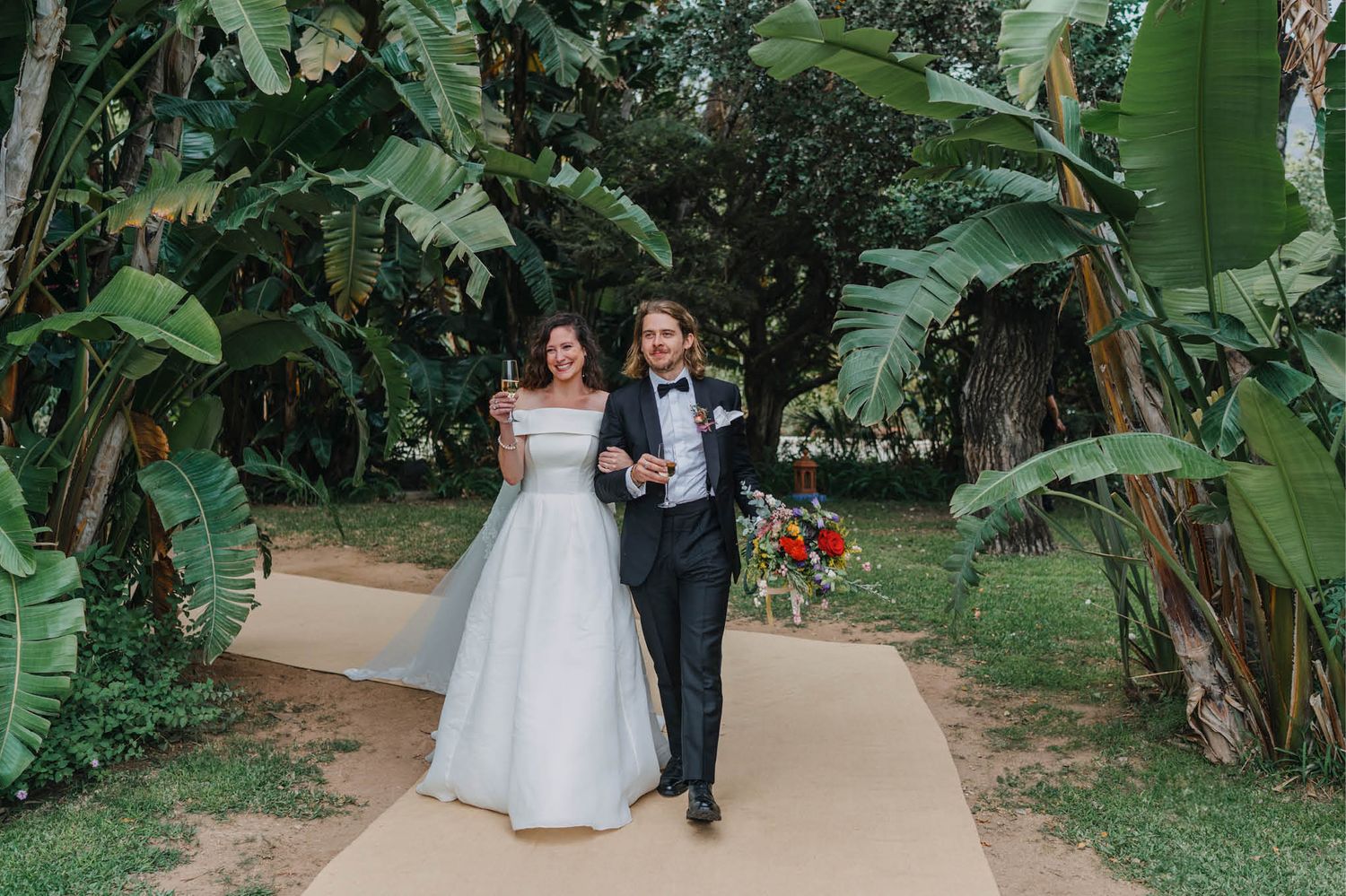 Wedding ceremony walkway lined with tropical plants and palm trees.