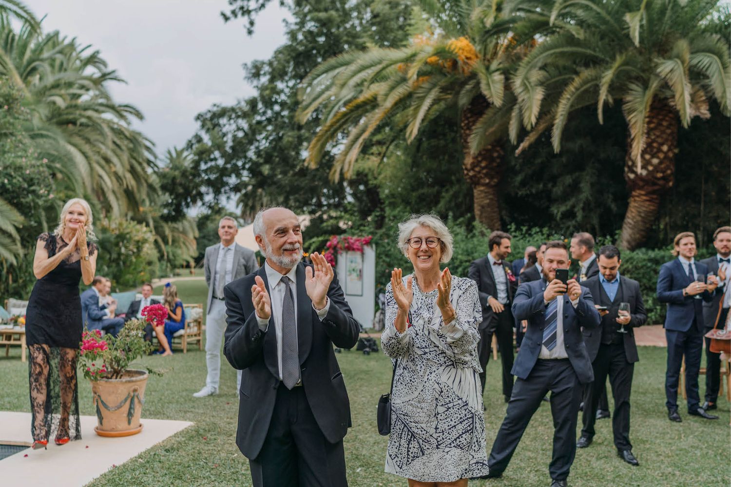 Outdoor wedding celebration with palm trees and lush garden landscaping.