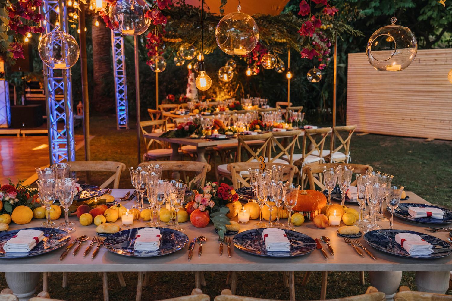 Elegant outdoor wedding table setting with autumn decor, string lights, and floral arrangements.