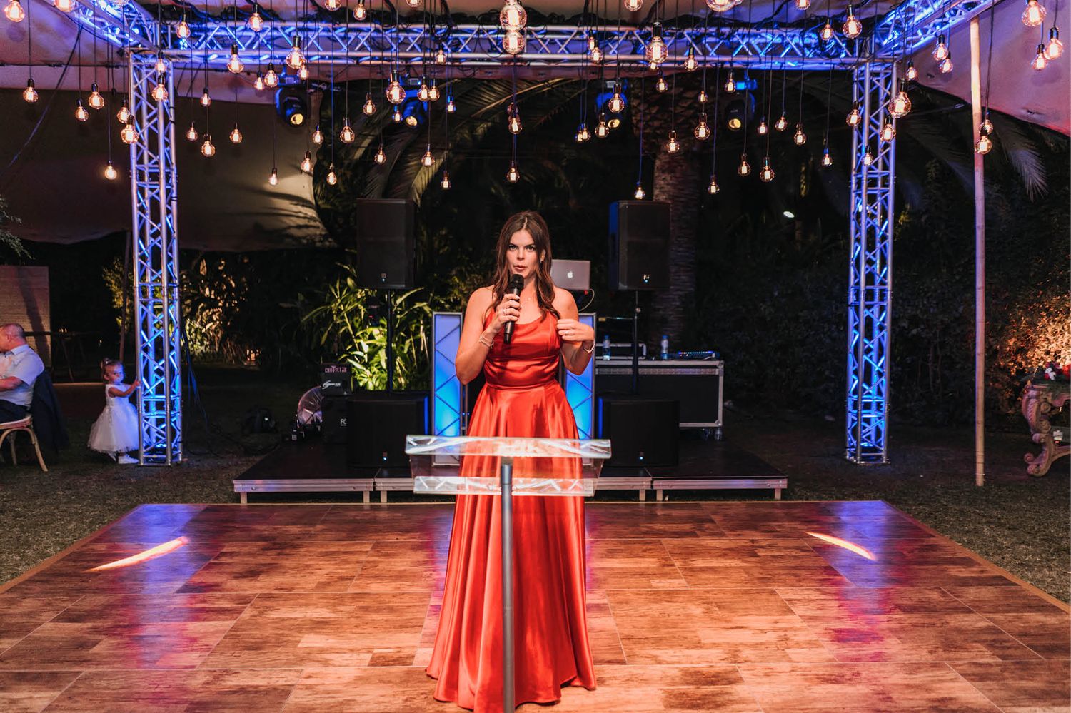 Evening performance on an illuminated dance floor under a tent with blue lighting.