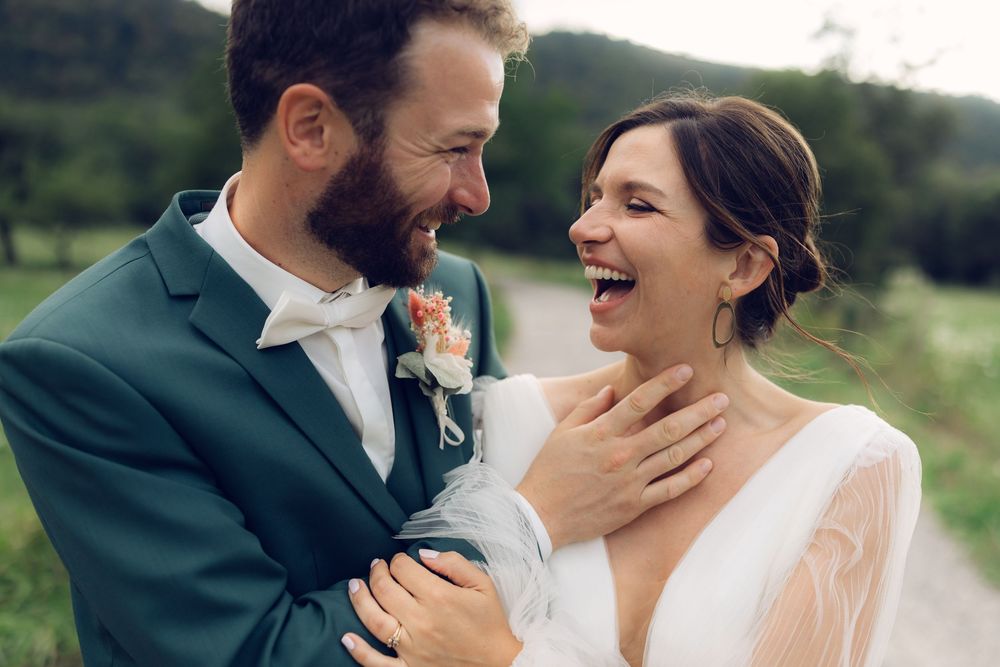A couple in wedding attire share intimate laughing moments together in a series of romantic outdoor portraits.