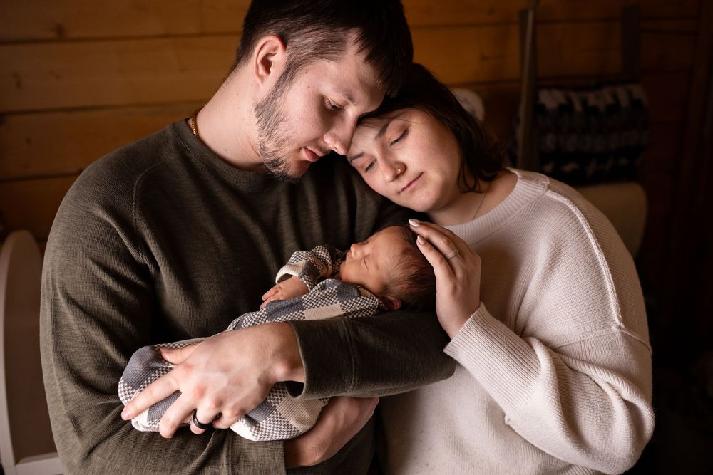 A tender moment between a couple in cozy sweaters as they embrace and rest their heads together.