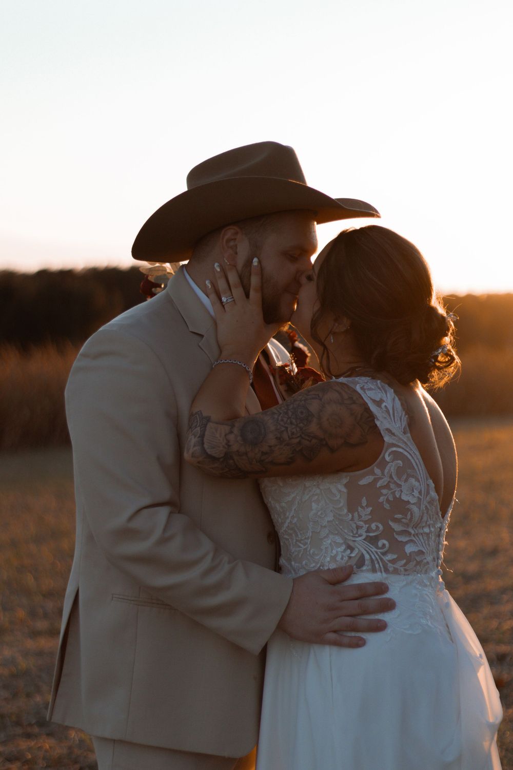 Romantic sunset silhouette of a couple embracing in a field.