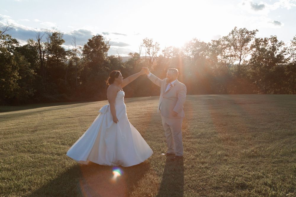 Bride and groom sharing a romantic moment in a sunlit field during golden hour.