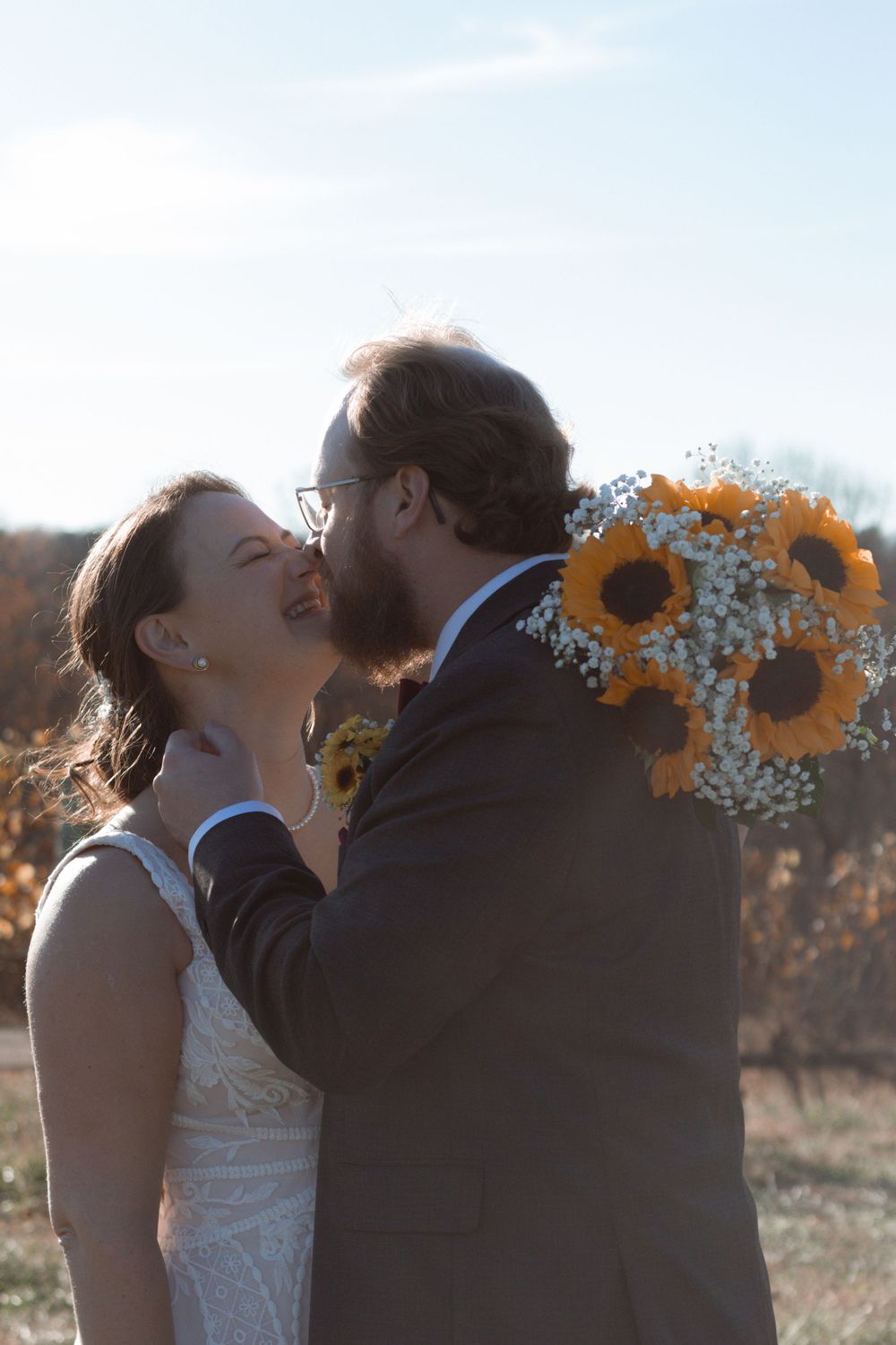 Romantic kiss scene in vineyard with sunflowers and fall foliage in background.