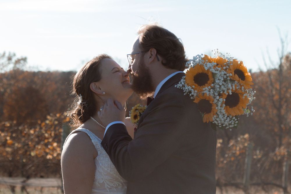Sunset wedding portrait in rustic vineyard with sunflower bouquet decor.