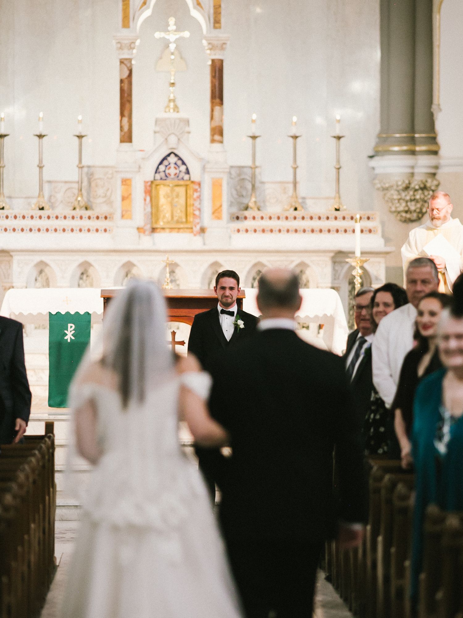 Wedding ceremony in progress inside a traditional church with white altar and candles.
