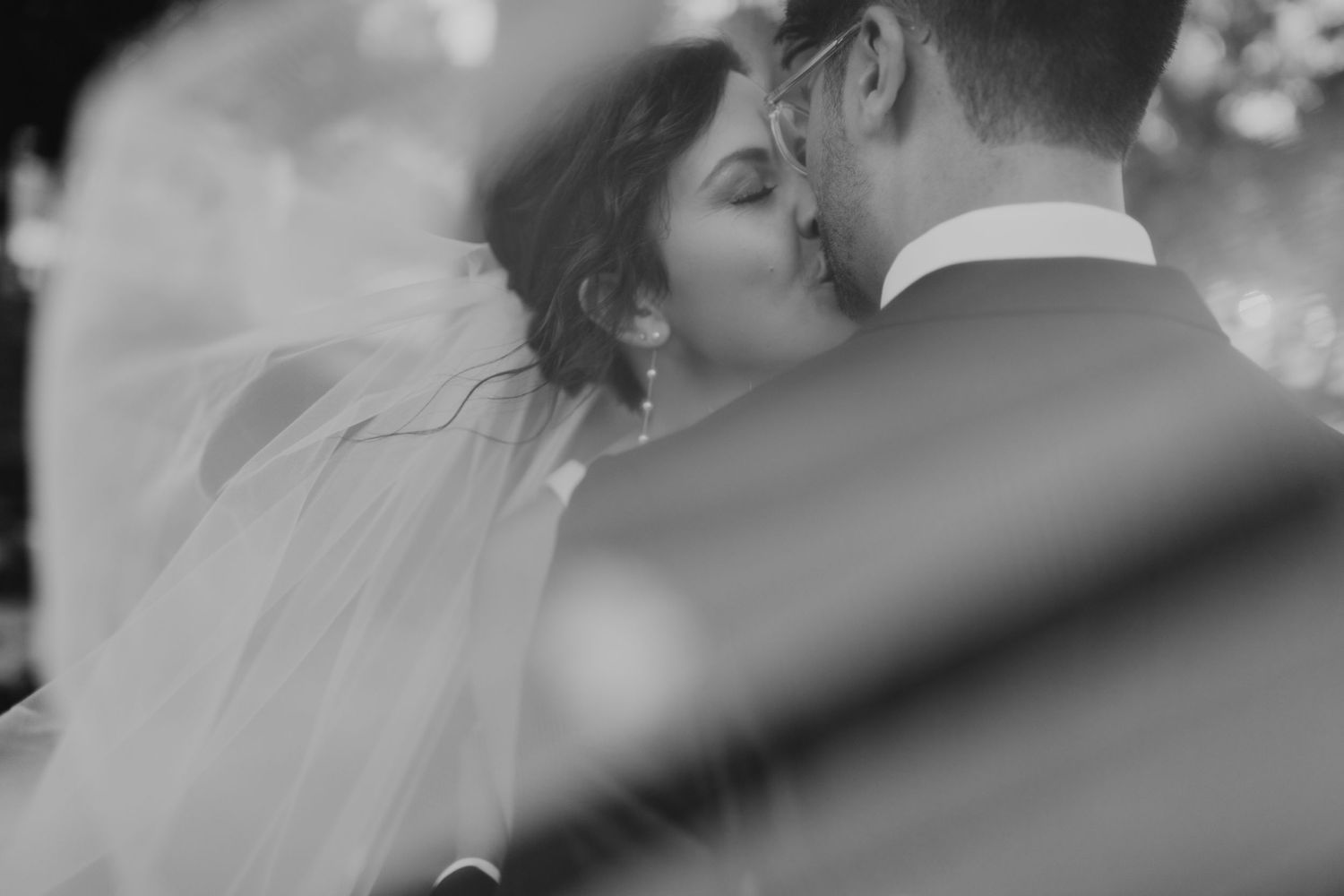 A romantic black and white portrait capturing an intimate wedding moment.