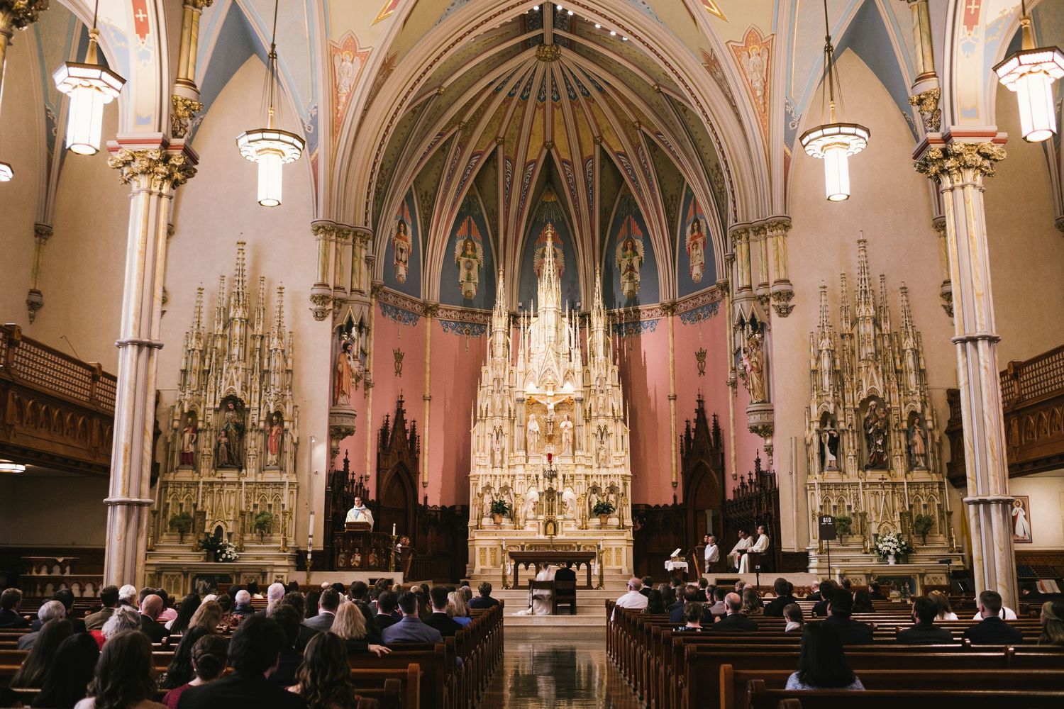 Interior of gothic cathedral with ornate altar and vaulted ceiling during ceremony.