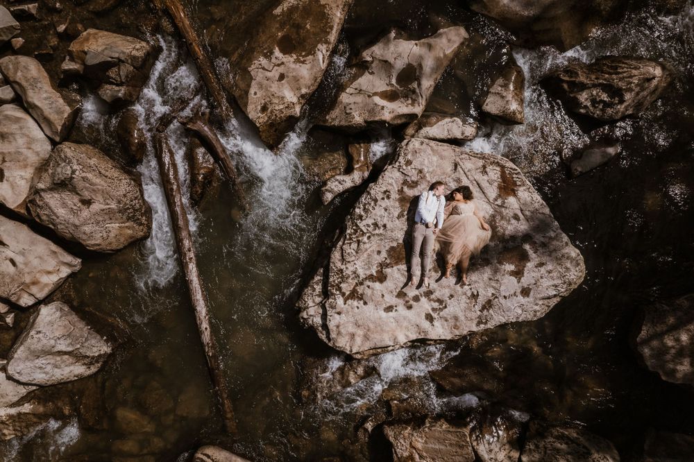 A waterfall cascades over rocky cliffs in a dramatic wilderness setting. Colorado Elopement Wedding.