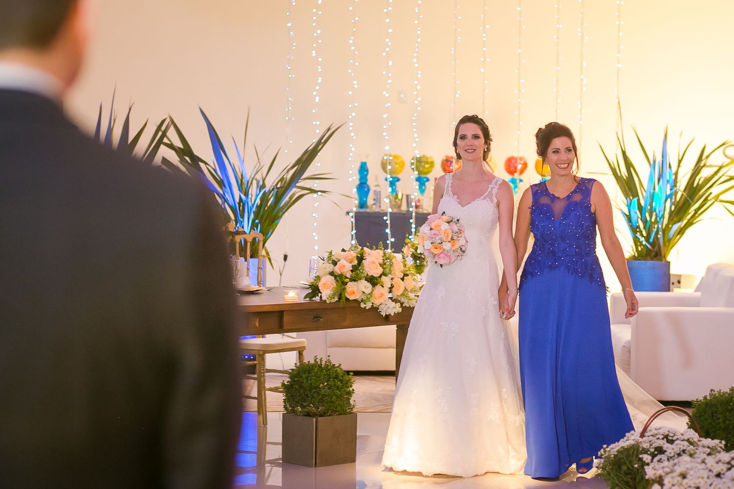 Wedding ceremony moment captured in an elegantly decorated indoor venue with blue and white color scheme.