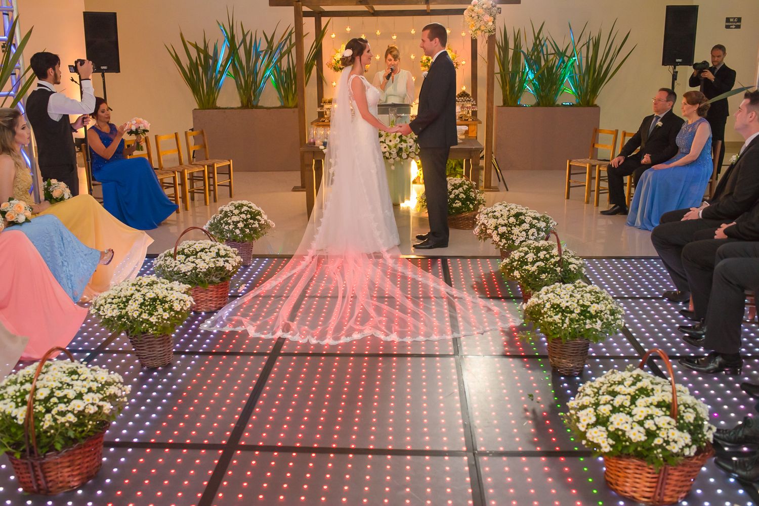 Wedding ceremony setup with floral arrangements and a decorative aisle runner in an indoor venue.