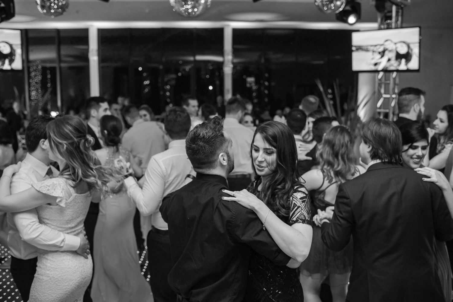 Black and white photo of wedding guests dancing and mingling at the reception.