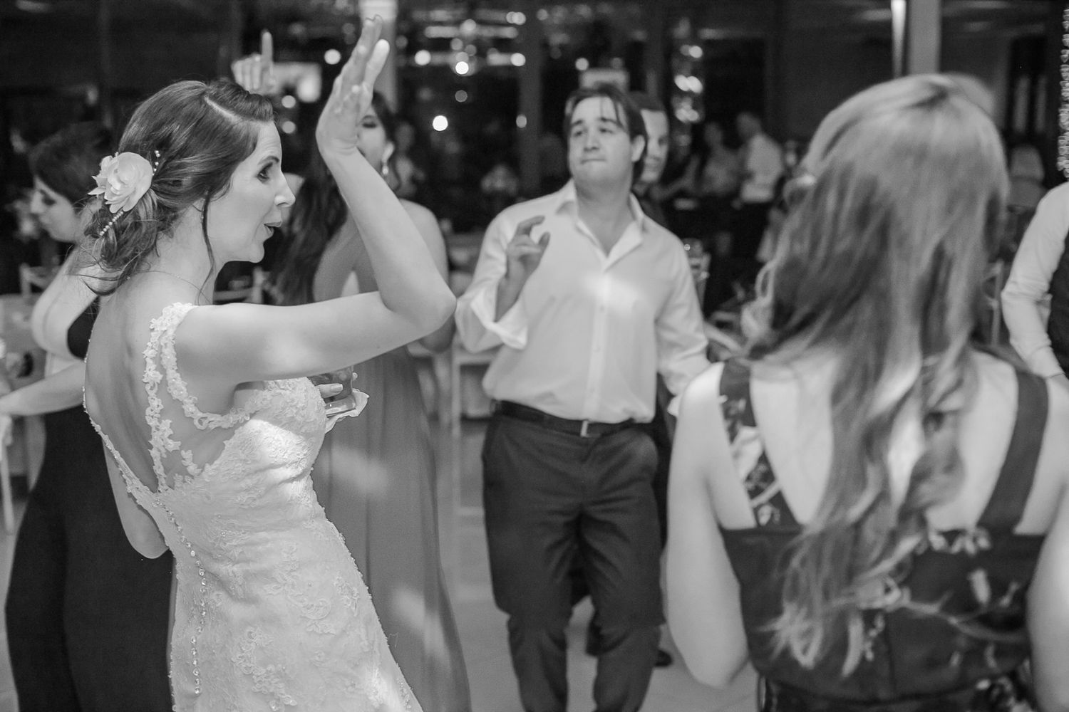 Wedding guests dancing energetically on a brightly lit dance floor during celebration.