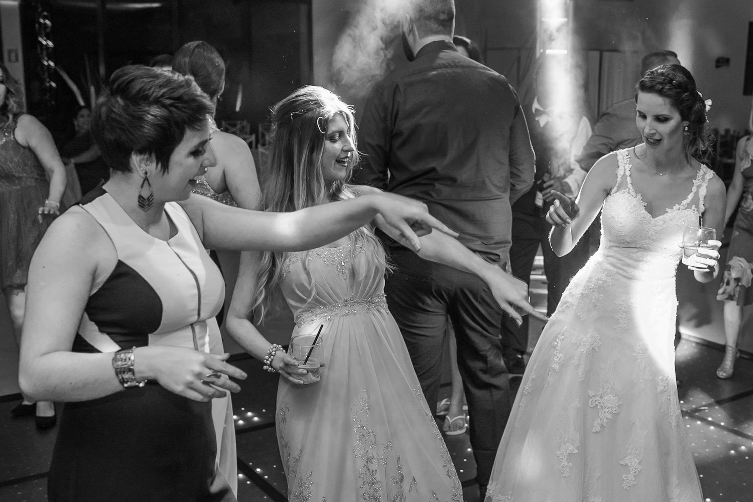 Wedding guests in formal attire dancing and celebrating on the reception dance floor.