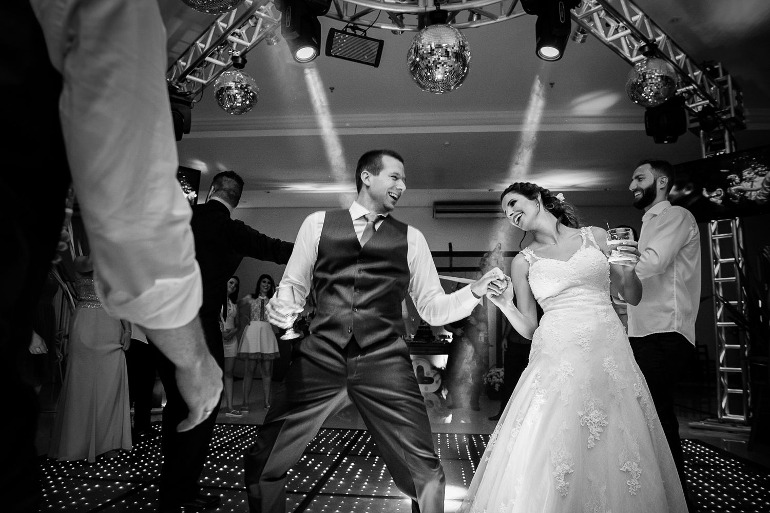 Couple performing energetic dance moves on their wedding reception dance floor.