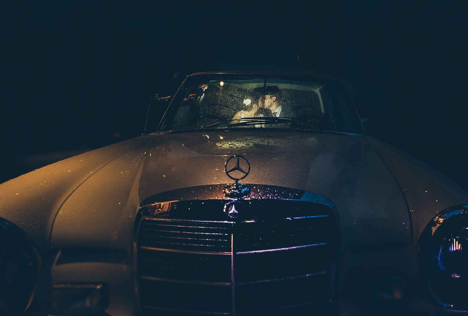 Classic Mercedes-Benz car front grille illuminated at night.
