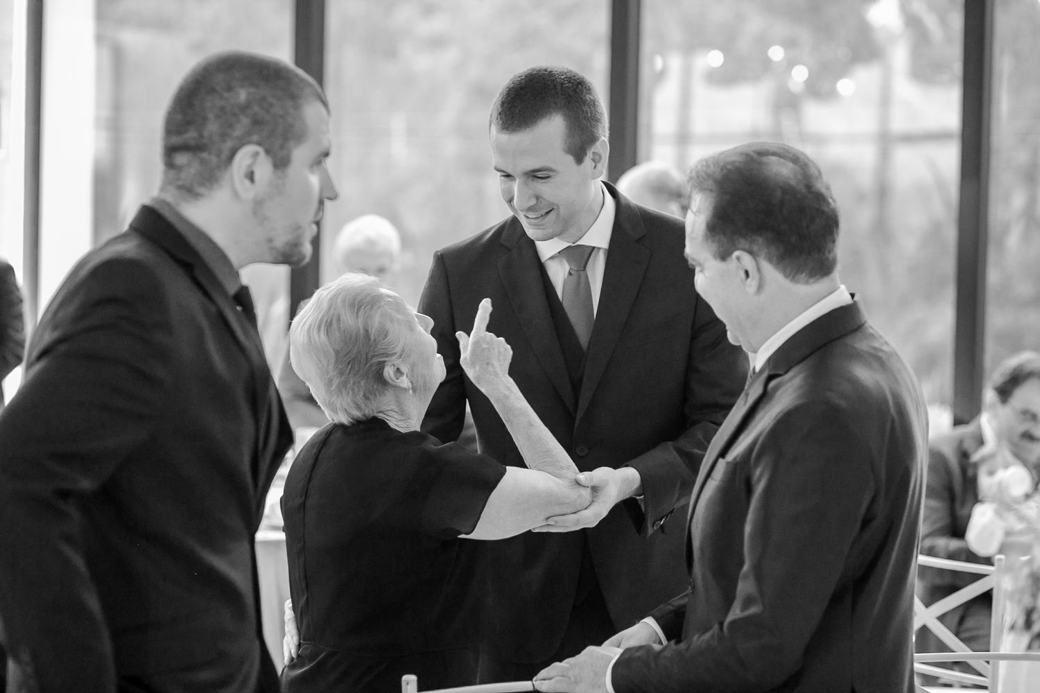 Group gathered in formal attire reviewing documents during an indoor event.