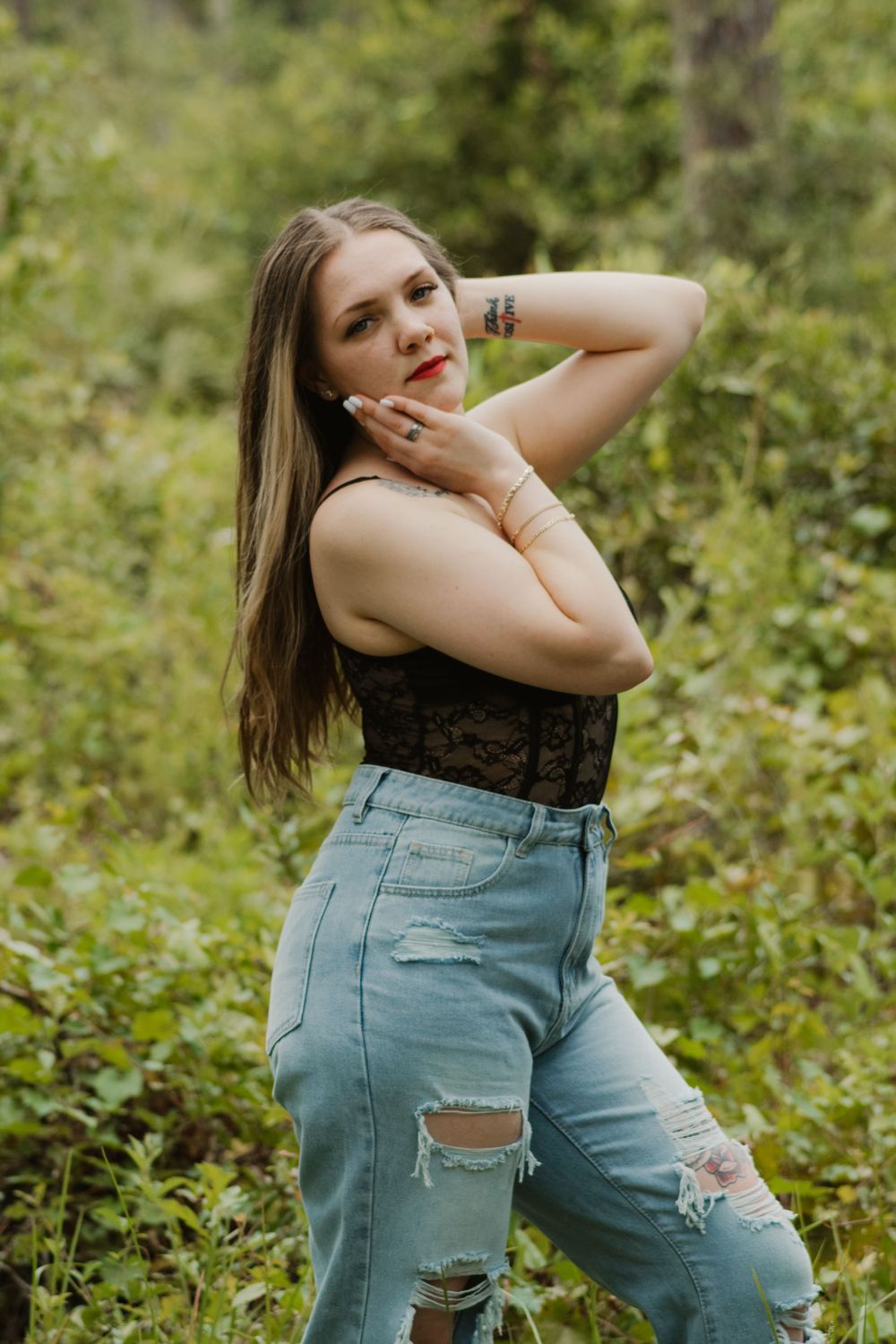 A series of outdoor portrait photos showing someone in ripped blue jeans and a black top posing against a green natural background.