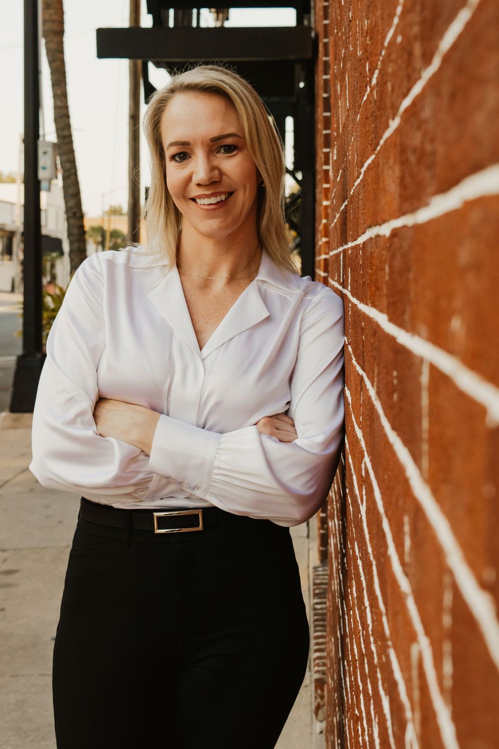 Professional headshots against a brick wall featuring a white collared shirt and warm natural lighting.