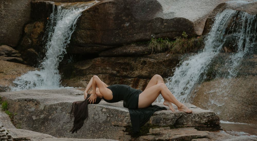 A waterfall cascades over rocky ledges surrounded by autumn foliage in a scenic forest setting. Diana's Bath's, New Hampshire