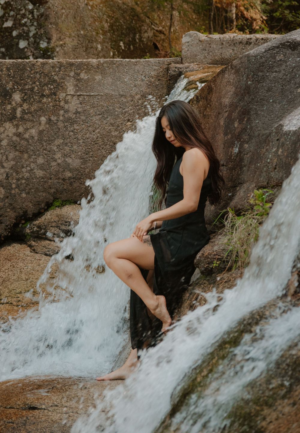 A waterfall cascades over rocky ledges surrounded by autumn foliage in a scenic forest setting. Diana's Bath's, New Hampshire