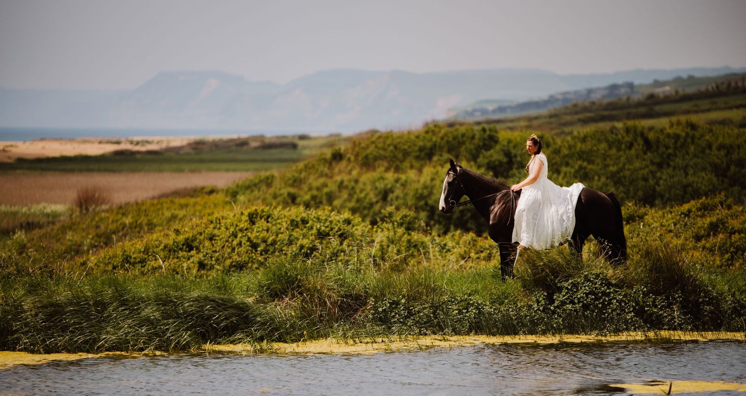West Bexington Wedding venue with sea view. Bride on horse back over looking Chesil Beach and bridport. Bridport wedding photographer