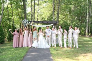Wedding party celebrates outdoors with bridesmaids in pink, groomsmen in white, and the bride and groom in the center.