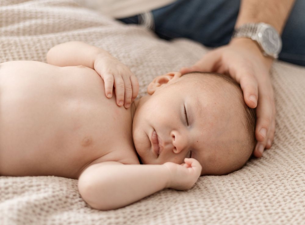 Sleeping baby lying peacefully on textured beige blanket.