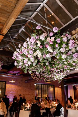 Stunning floral chandelier with pink and white roses hangs in industrial wedding venue.