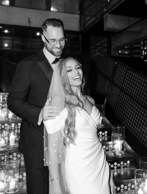 Elegant wedding couple embraces in a romantic venue with soft candlelight and industrial decor.