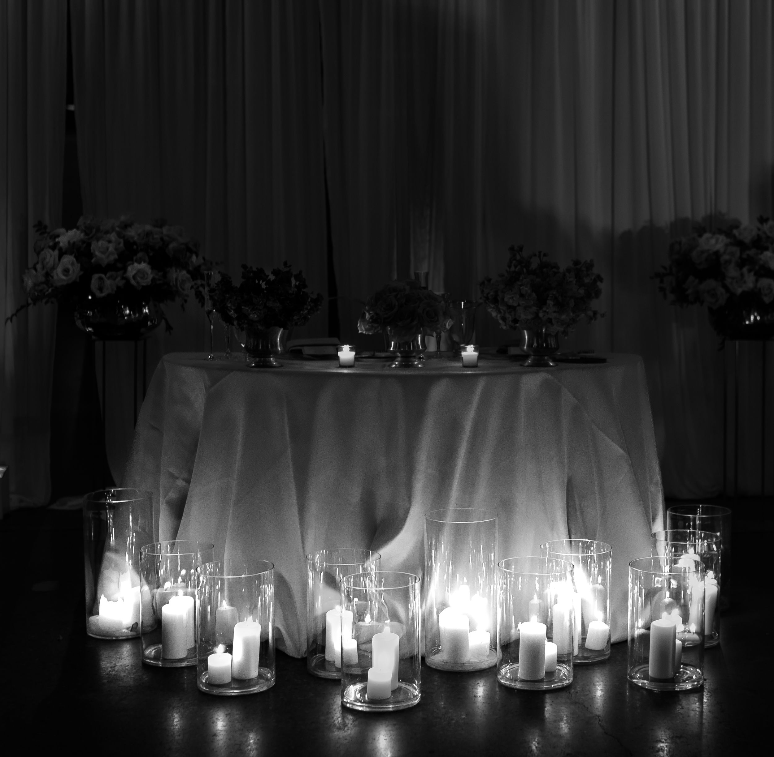 Romantic candlelit wedding table setting with dramatic black and white lighting.
