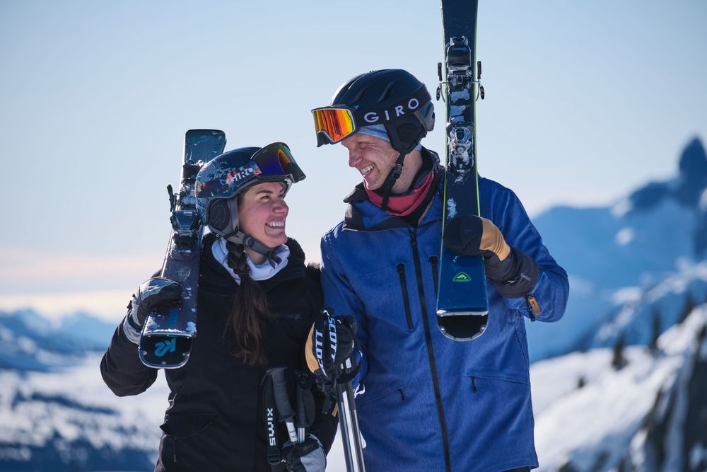 Skiers enjoying a scenic winter day in snowy mountains with blue skies.